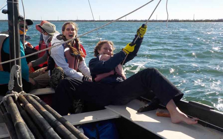 a person holds a rope on a sailboat during an outward bound expedition in florida
